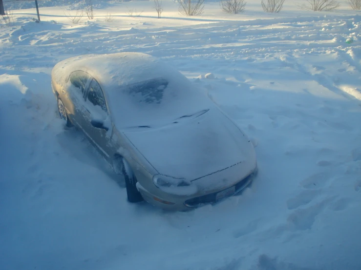 a parked car sits in deep snow with only the hood down