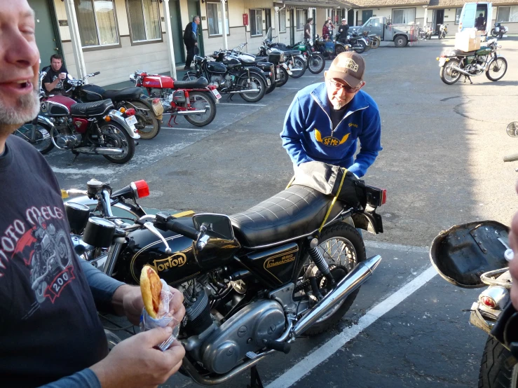 a group of people are sitting around motorcycles