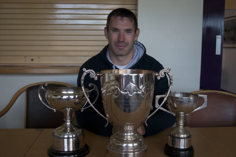 a man is sitting in front of three trophies