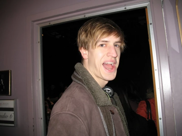 young man in open doorway looking to camera with mouth open