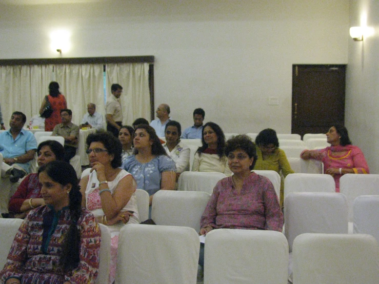 people sitting in rows at public event in building