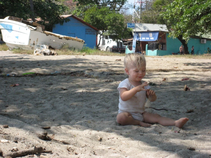 a child sitting on the sand holding a toy