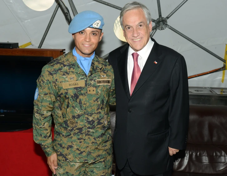 an old gentleman in a blue hat and uniform standing next to a man