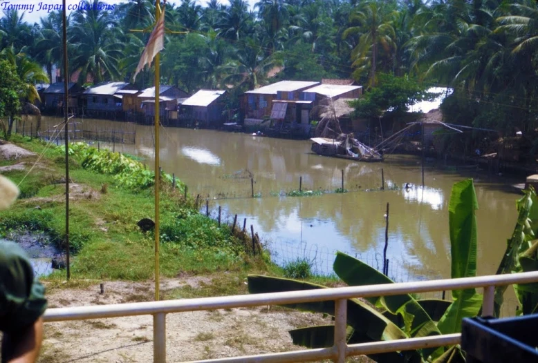 a person standing at the side of a river looking out to a village