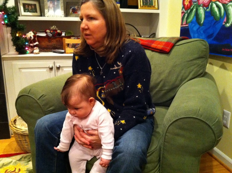 a woman sits on a couch while holding a baby