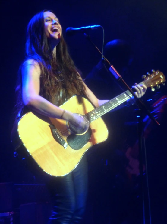 the woman is playing her guitar at the microphone