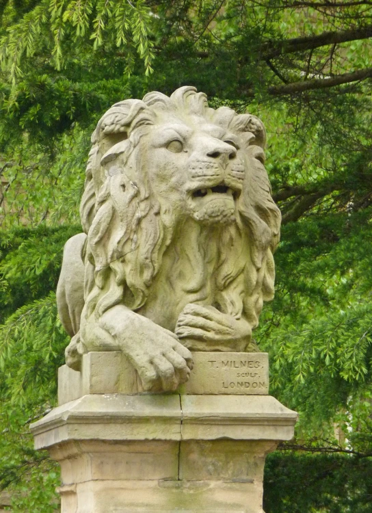 a large stone lion statue in front of some trees