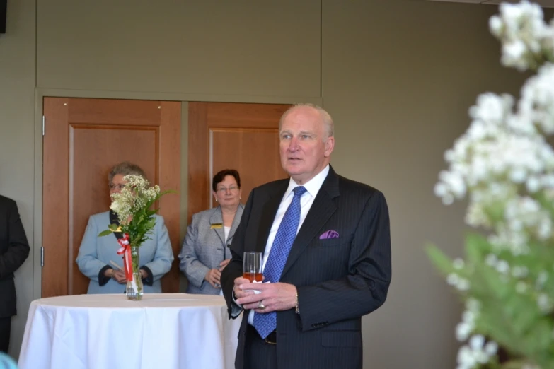 a man in a suit and tie holding a glass