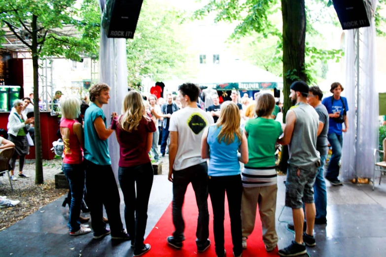 group of people in a courtyard, with the stage and people looking on