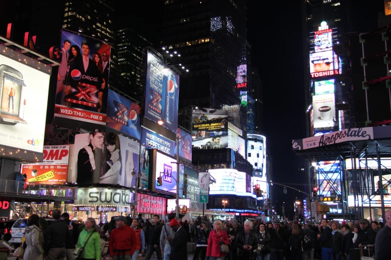 a busy street with lots of people walking and advertits