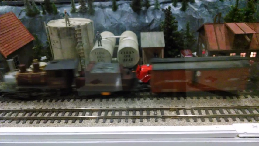 model train with cars and trees on it in front of a window