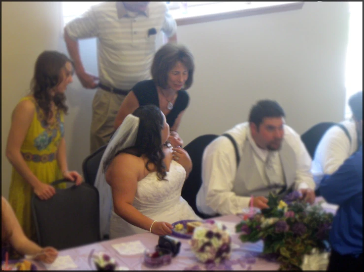 two couples cut into their wedding cake with one of them looking over