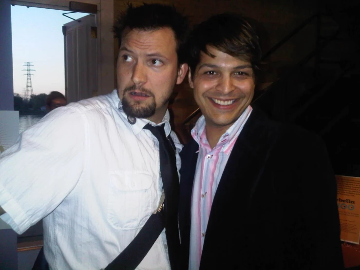 two men standing next to each other and wearing neck ties