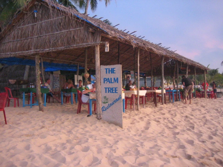 a bunch of chairs sitting under a thatched roof