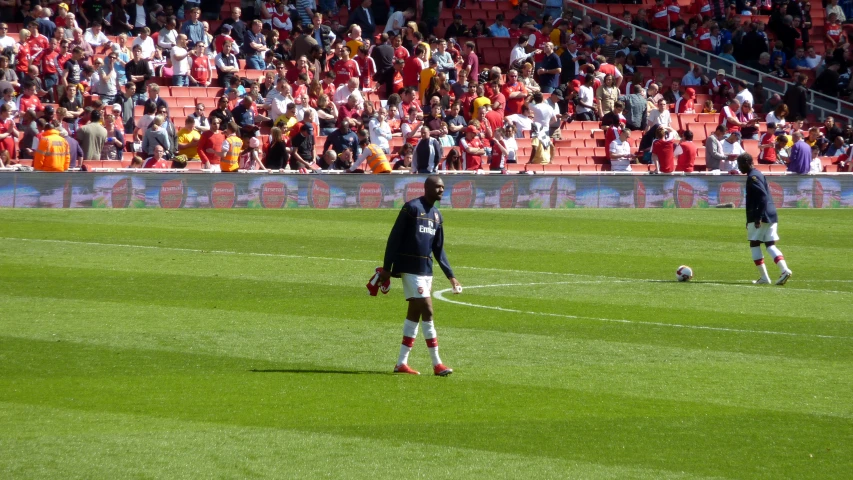 a soccer player prepares to kick the ball while other players stand in the background