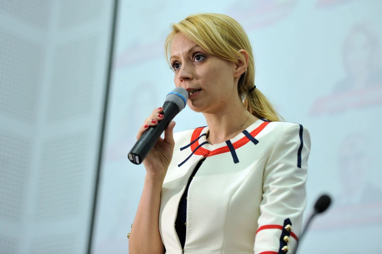 the blonde woman is holding a microphone and giving a speech