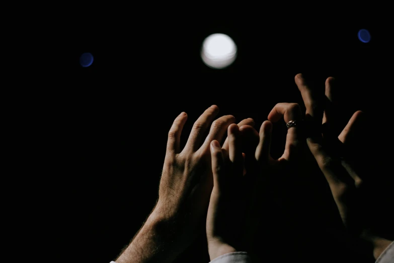 two people with their hands reaching towards the moon