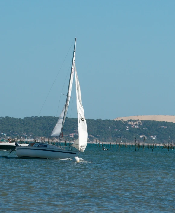 a large sailboat sails along the water with another boat in the background