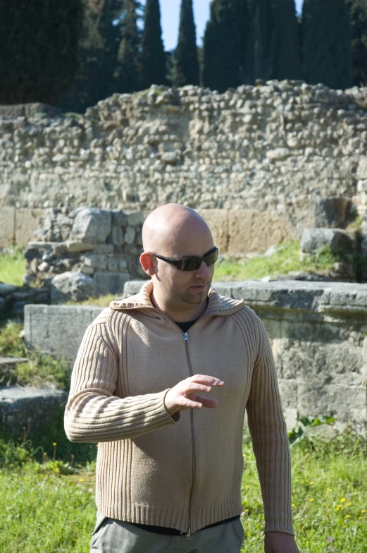 a man with shades on in front of a large rock