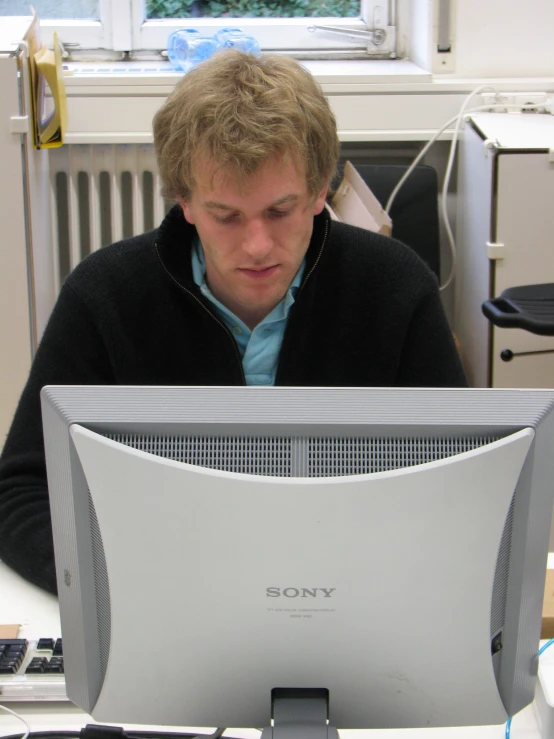 a man looks at a monitor while sitting at a desk