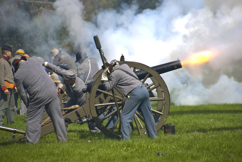 two men standing next to each other near a cannon