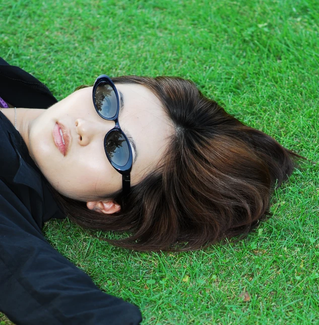 a girl in a suit with some glasses laying on the grass