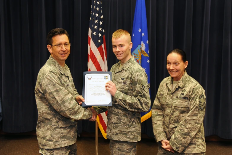 a military man holding an award to another soldier