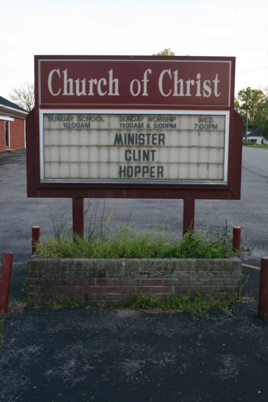a church sign in front of a brick and cement building