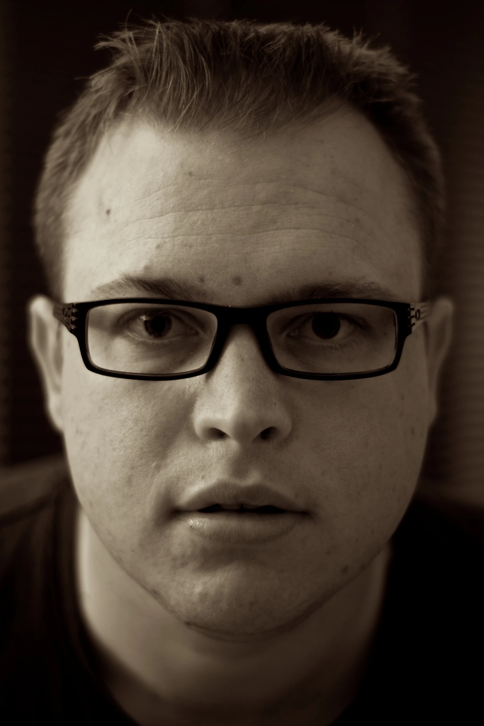 man with black glasses looking very serious in sepia