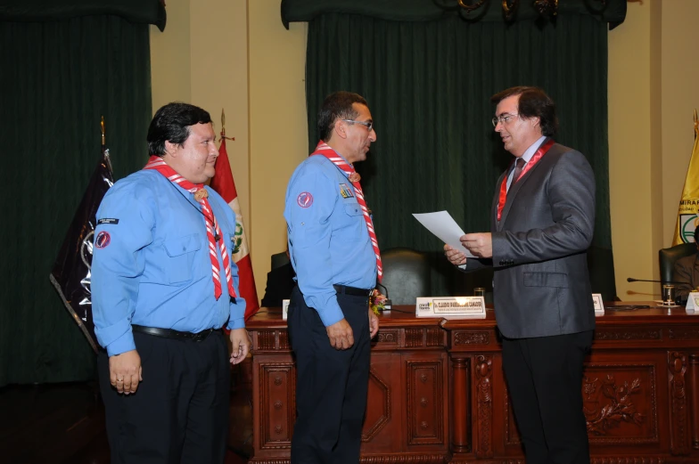 three men in suits and ties at an official meeting