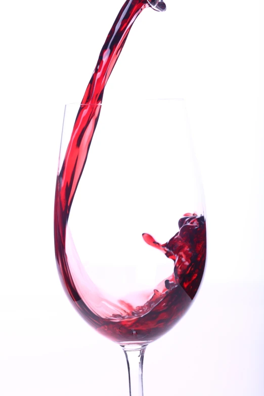 a glass filled with red wine splashing out of it