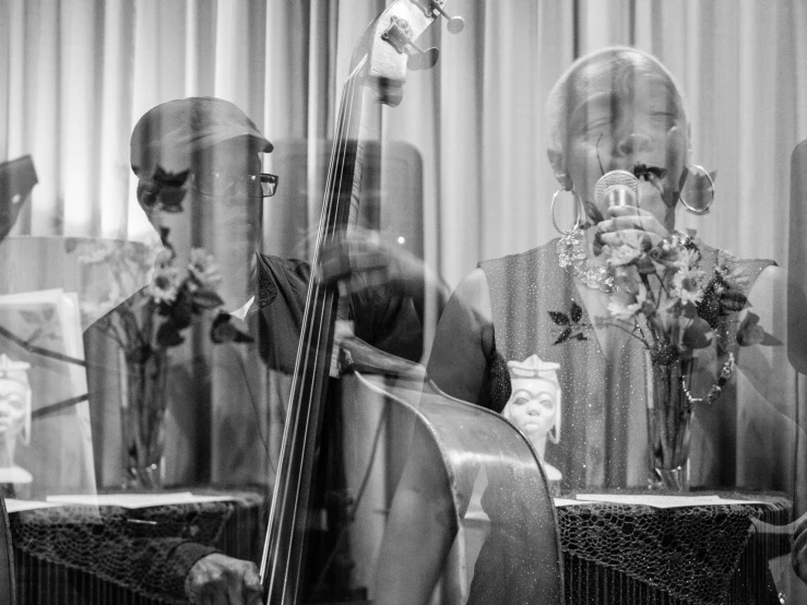 a man with a cello in front of him is looking at another musician in the background