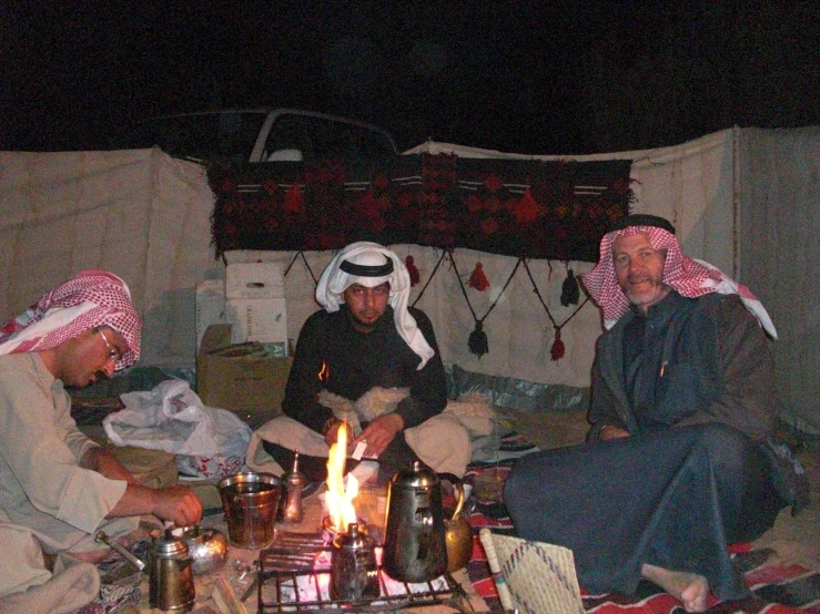 people sitting on couches around a lit candle at night