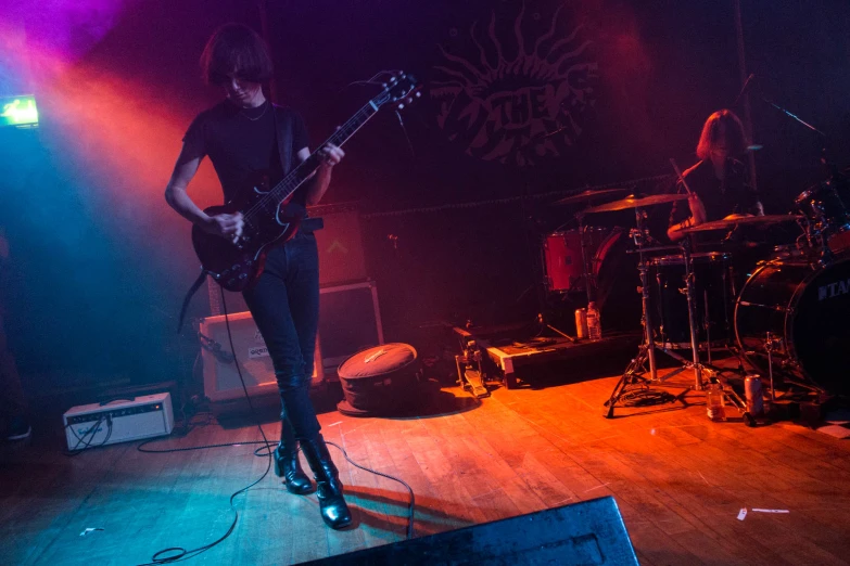 guitarist performing at a concert in front of drums