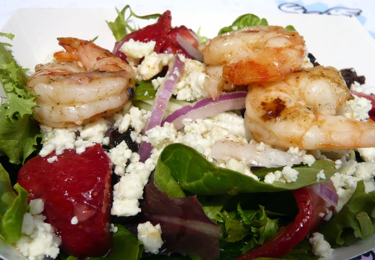 there is salad with shrimp and strawberries in it