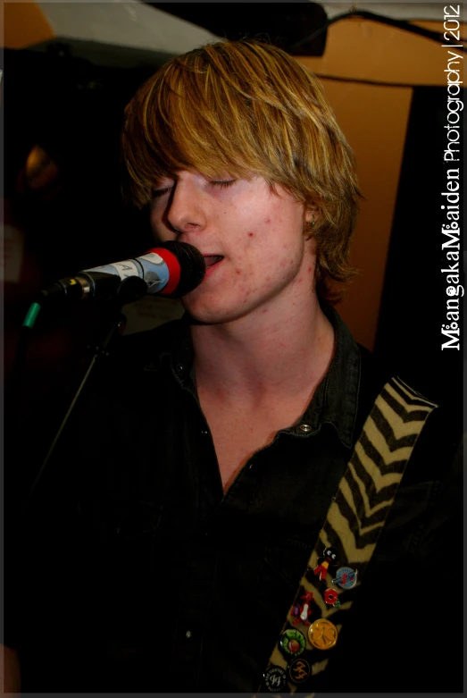 a young man is singing into a microphone