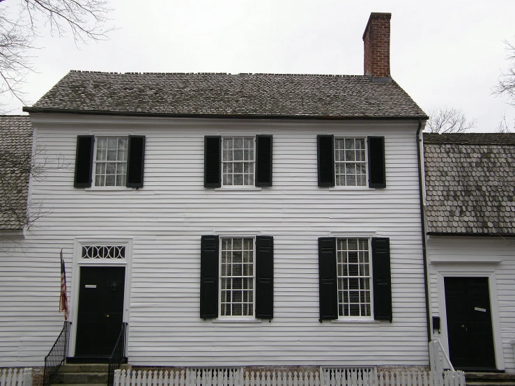 the white colonial home is very old and has black shutters