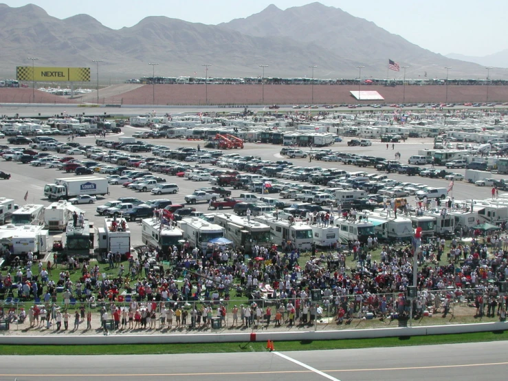 a large crowd of people standing around many tents at a large motor vehicle event