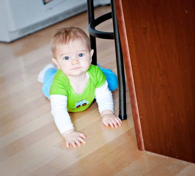 a small boy crawling under the desk