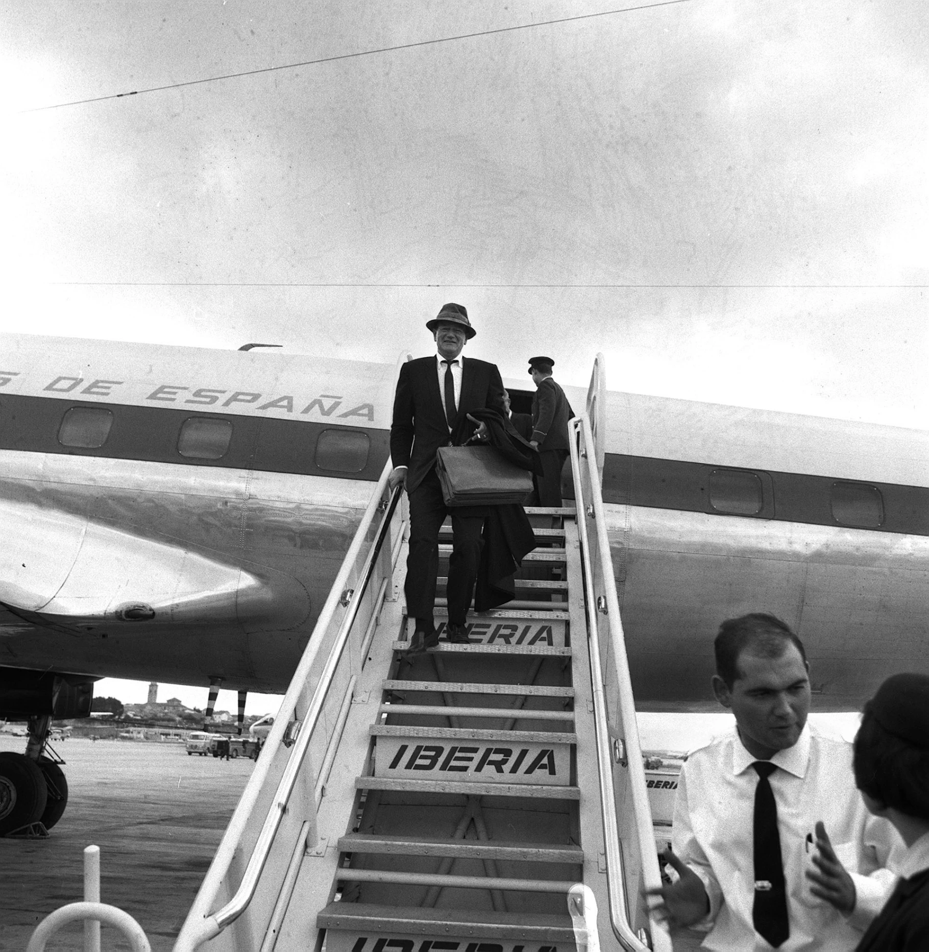 black and white po of two men walking down stairs to an air plane