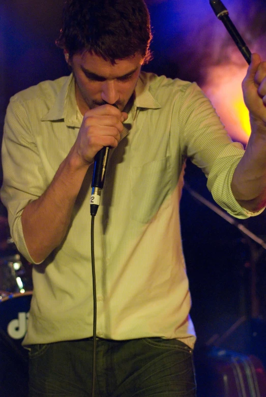 a man singing into a microphone while holding it to his ear