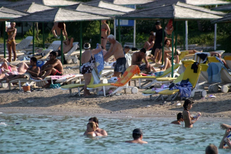 a beach full of people sitting and standing around