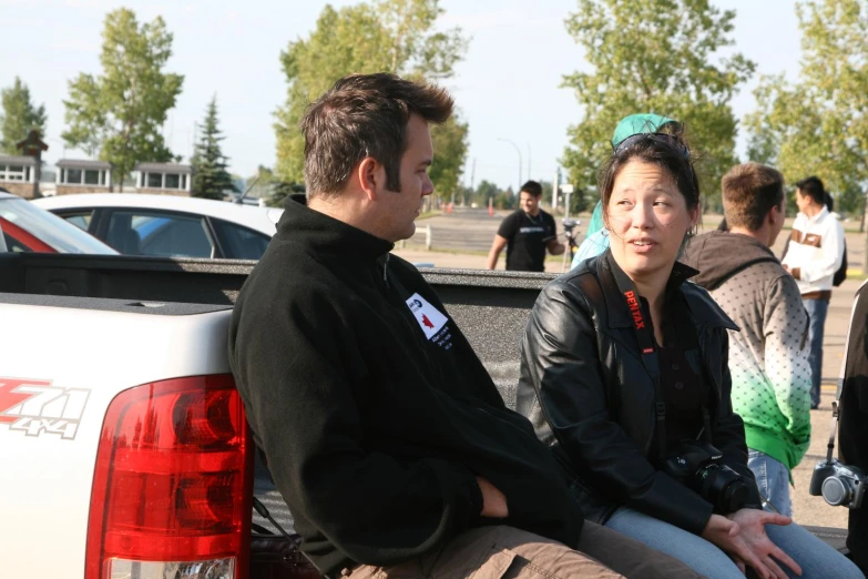 three people in the back of a pickup truck