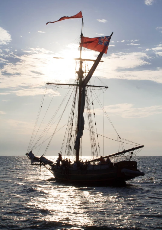 a sailboat with an orange flag sailing through the ocean