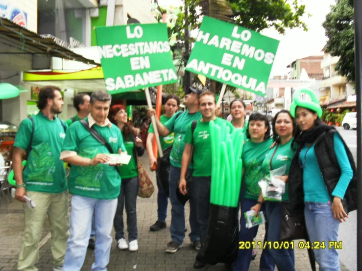 many people are in green shirts holding signs and looking at the camera