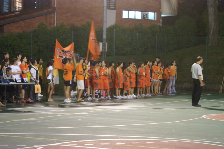a crowd of basketball players stands on the side of a court