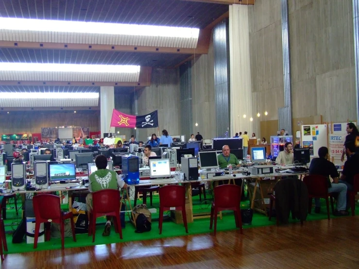 many people sit at computer desks in an open room