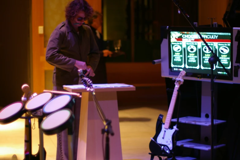 a man standing next to a table and a tv with an electronic keyboard