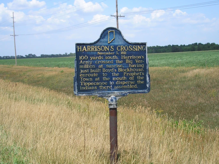 this sign points to harrison crossing, in the background is grassy field