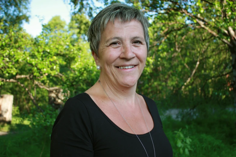 an older woman standing next to a forest